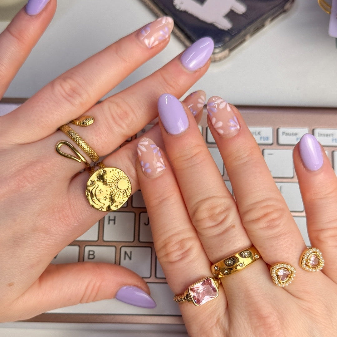 Close-up of hands with gold rings and purple nail polish against a keyboard background